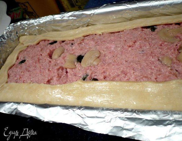 Свисающие с формы края теста загибаем, подрезав уголки при помощи ножниц, внутрь. Смазываем слегка взбитым вилкой белком.