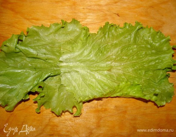 У листиков салата оборвать нижнюю часть. Для одного рулетика понадобится два листика. Положить их внахлест.