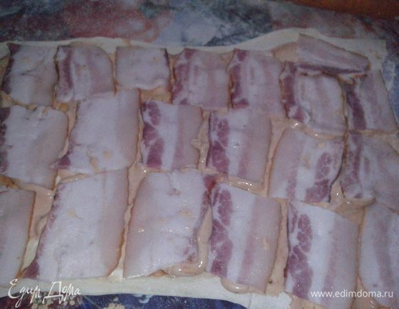 Тесто раскатать тонким слоем, смазать кетчупом и майонезом, выложить плотно нарезку бекона.