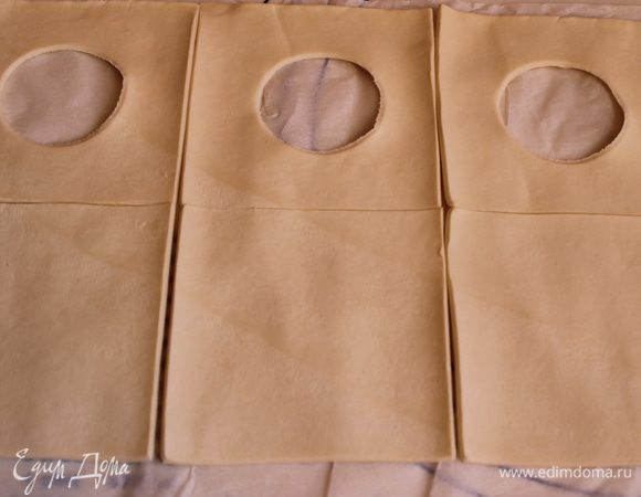 Развернем готовое слоеное тесто. Разрежем на квадраты 10 на 10 см, нам нужно парное число. В половине квадратов вырежем рюмкой серединку.