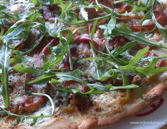 Вынуть пиццу из духовки, посыпать рукколой, сбрызнуть оливковым маслом и лимонным соком.