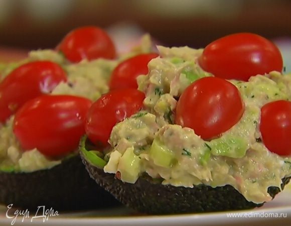 Чашечки авокадо наполнить начинкой, сверху выложить половинки помидоров.