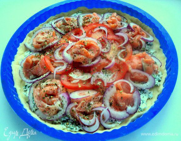 Поверх сыра разложить филе семги, помидоры и полукольца лука. Посыпать итальянскими травами.