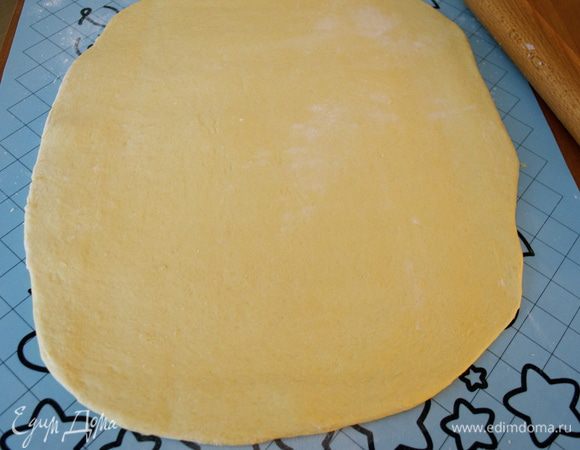 По истечение указанного времени достать тесто из миски, выложить на слегка припыленную мукой поверхность и раскатать в пласт толщиной 3-4 мм. 