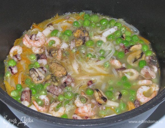 Через минуту опустить горошек и морепродукты. Горошек должен быть предварительно разморожен. Посолить и поперчить по вкусу. Варить еще полторы минуты.
