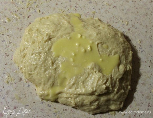 Затем выкладываем тесто на смазанный маслом стол, сверху на тесто выливаем ложку растопленных жиров, и вмешиваем их в тесто. И так добавляем по ложечке, пока все жиры не вмешаем. Месить тесто до тех пор пока оно не перестанет липнуть к рукам и столу, примерно минут 15.