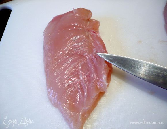 Теперь положим наше филе под пищевую пленку и ту половину, которая более тонкая (как раз на нее указывает нож) отобьем молотком. Отбитой частью филе мы будем закрывать надрезанную и начиненную часть филе. 
