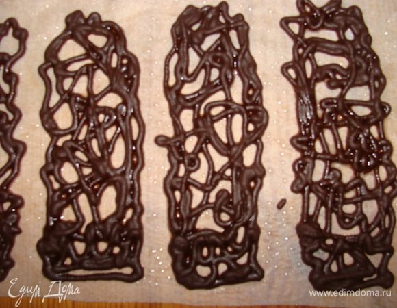 Растопить шоколад с маслом на водяной бане. Используя рукав, сделать фигурное украшение. Для этого надо пекарскую бумагу или кальку смазать растительным маслом и выдавить на нее тонкой струйкой горячую шоколадную массу. Дать застыть. Можно убрать в морозилку на несколько минут, так шоколад будет легче отделяться от бумаги. Нужно оставить немного растопленного шоколада и отдельно масла.