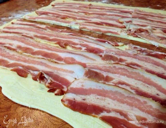 Поверх теста выложить бекон. И разрезать тесто напополам.