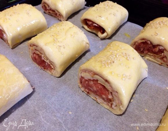 Противень застелить пергаментной бумагой. Выложить слойки, смазать их яйцом и присыпать кунжутом!