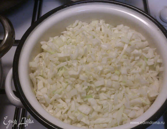 Начинаем готовить начинку. Капусту рубим мелко, я стараюсь, чтобы кусочки были 0,5*0,5 см, ну или чуть крупнее. Для этого количества пирогов я рубленой капустой заполняю 2-х литровую кастрюльку. Сверху солим (2 ч/л). Никакой воды не добавляем!!!!! Ставим под крышку на самый маленький огонь.
Следим, чтобы не подгорела, помешиваем периодически. Наша задача - поймать тот момент, когда капуста начнет становиться прозрачной, ни в коем случае не коричневеть (это означает, что мы ее переварили. Не криминал, конечно, но цвет начинки в пироге будет темный.) Но и хрустеть, как сырая капуста, она не должна. Ориентир по времени - 20-25 минут.