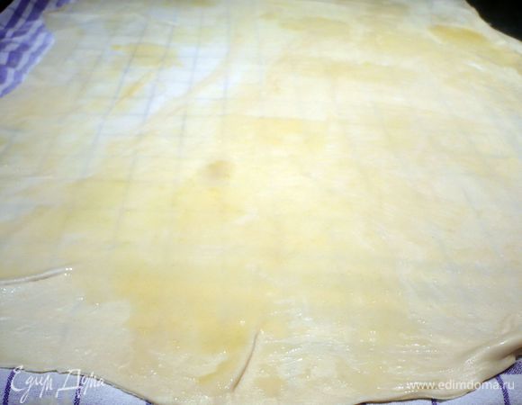 Когда тесто будет равномерно тонким, нанесем на него аккуратно кисточкой растопленное сливочное масло. Затем распределим начинку, оставляя по краям примерно по 5 см свободными. Начинку необязательно выкладывать так, чтобы она полностью покрывала тесто, достаточно выкладывать ее как бы вкраплениями, и не перекладывать ее, я же не удержалась, и тесто в некоторых местах у меня прорвалось. 