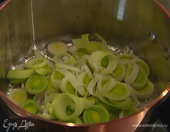 Разогреть в кастрюле оливковое масло и обжарить порей до прозрачности.