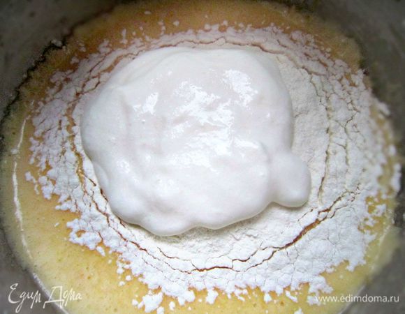 В отдельной ёмкости соедините соду со сметаной и оставьте на 5 мин. Муку просейте, смешайте с разрыхлителем и всыпьте в масляно-яичную смесь порциями, чередуя со сметаной и перемешивая после каждого добавления.