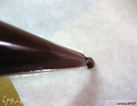 Шоколад растопить на водяной бане или в микроволновой печи. Дать ему немного остыть и переложить в кондитерский мешок (у меня это одноразовый полиэтиленовый). Отрезать у мешка небольшой кончик, чтобы можно было рисовать не очень толстыми шоколадными линиями.
