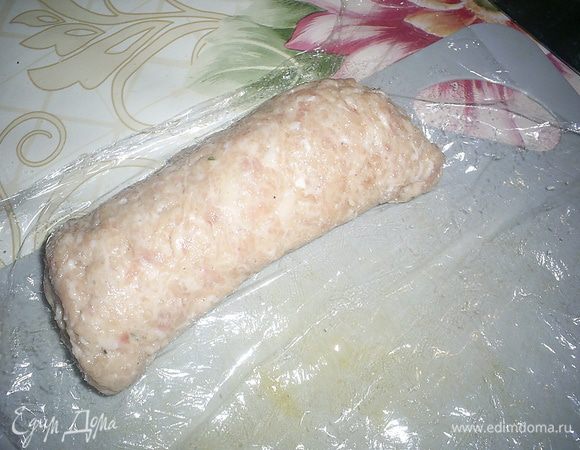 Теперь скручиваем плотный рулетик с помощью пленки. Руками через пленку приминаем фарш, формируя красивую ровную сардельку.