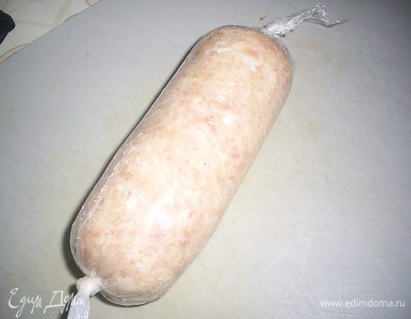 Заворачиваем полученную сардельку в несколько слоев пищевой пленки, катаем по столу для уплотнения и завязываем концы пленки узлом.