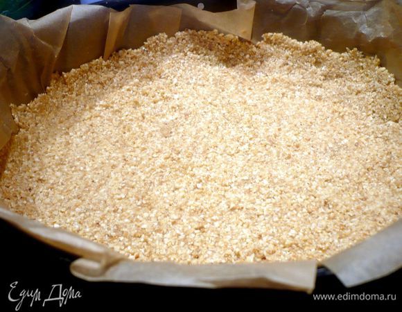 Выложить бока и дно формы (диаметром 24 см) бумагой для выпечки. Разогреть духовку до 180 градусов. Крупно порубить 2 столовые ложки орехов.  Растопить масло, смешать его с 75 г сахара и медом, дать слегка остыть. Остальные орехи измельчить в блендере и смешать с масляной массой. Выложить ореховой смесью дно формы и бока и утрамбовать при помощи ложки. Убрать форму в холодильник.