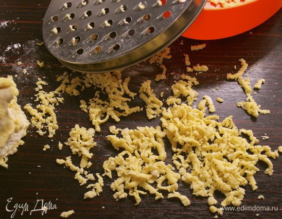 Достать из холодильника тесто и как следует обвалять его в муке. Дело в том, что раньше я сталкивалась с совершенно иным способом приготовления таких шпетцле, как самостоятельного блюда!... И там тесто должно получаться достаточно жидким, чтобы затем пропустить его через подобие дуршлага прямо в кипяток и отваривать клецки...( http://www.edimdoma.ru/retsepty/54102-tirolskie-kletski-so-shpinatom-spinatsp-tzle ) Здесь же тесто получается достаточно крутым и его предлагается тереть на крупной терке прямо в кастрюлю. Я для начала натерла тесто на стол...