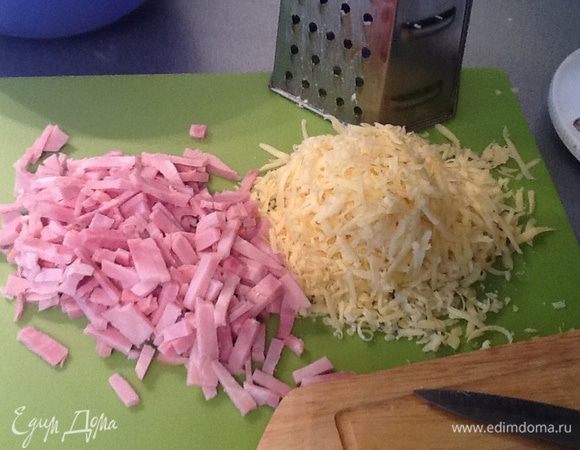 Сыр натереть на крупной терке, ветчину нарезать тонкой соломкой, добавить к тесту, перемешать.