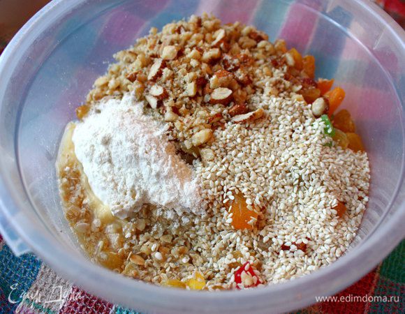 Затем в миску с овсянкой добавить орехи, кунжутные семечки, цукаты, курагу (заранее нарезанную полосками), изум, масло, муку пшеничную и овсяную.
Все тщательно перемешать.