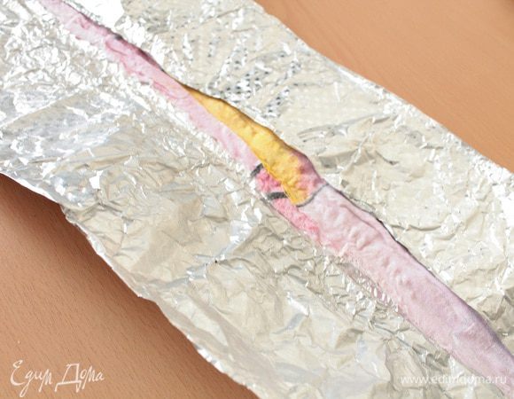 Предварительно нагреть духовку до 180 градусов, дно формы для запекания выстелить пергаментом, смазать пергамент маргарином,посыпать манкой, излишки стряхнуть. Для того, что бы бисквит во время выпечки не поднялся горкой надо поступить так: тонкое полотенце или кусок х/б ткани сложить вдвое, намочить холодной водой и отжать, затем берем фольгу и заворачиваем в нее ткань, вот так.