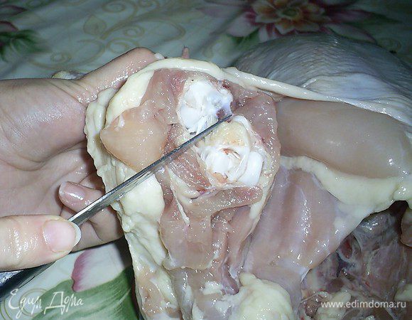 Отделяем осторожно кожу на бедрышках, вплоть до сустава. Теперь снова переворачиваем курицу — так будет удобнее перерезать сустав. Аккуратно, стараясь не повредить кожу, перерезаем сустав и отделяем голень. С нее кожу мы снимать не будем. Аналогично поступаем со второй голенью.