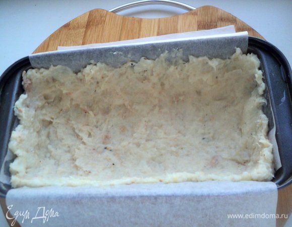 Форму размером 20х10 см застелить бумагой для выпечки, смазать растительным маслом.  Выложить рыбно-рисовую массу и равномерно распределить по дну и стенкам формы. Немного массы оставить для верхнего слоя.