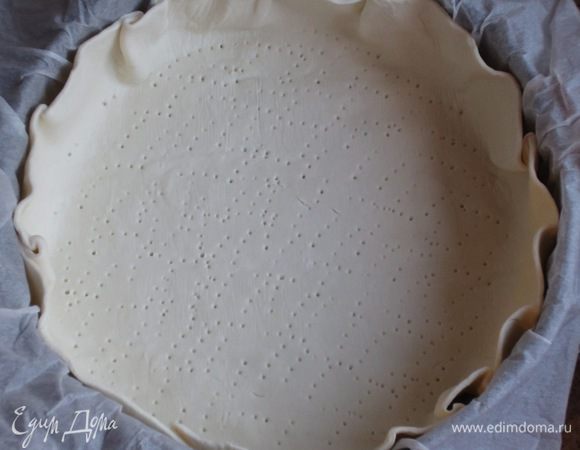 Пекарскую бумагу намочить водой , хорошо отжать и  выстелить дно  формы диаметром 24 см. Слоёное тесто раскатать в круг диаметром 30 см, выложить в форму и наколоть вилкой.Поставить в холодильник.
