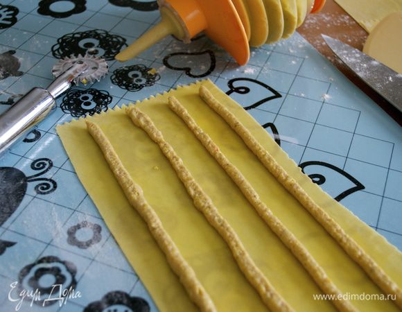 Подготовленный пласт теста смазать с помощью кисточки взбитым яйцом. С помощью кулинарного мешка с тонкой ровной насадкой нанести полоски начинки. 4 или 5, в зависимости от ширины пласта... Я после приспособилась и делала по 5 полосок начинки, экономя и тесто, таким образом. 