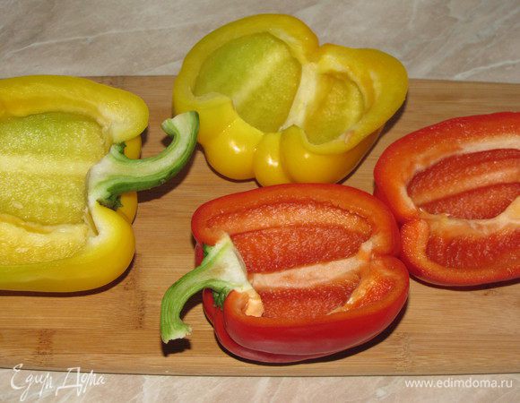 Перцы разрезать вдоль на две части, вместе  с плодоножкой. Удалить семена и белые перепонки.