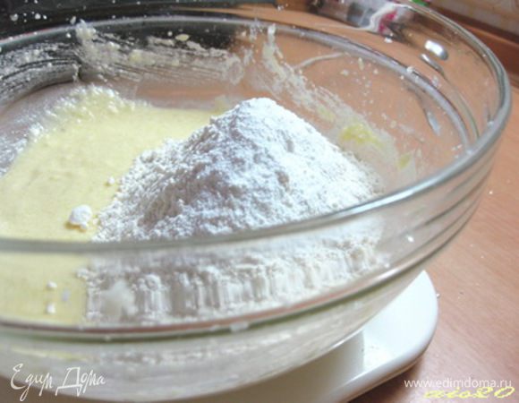 Муку смешать с разрыхлителем, просеять, добавить в творожную массу и взбить до однородного теста.