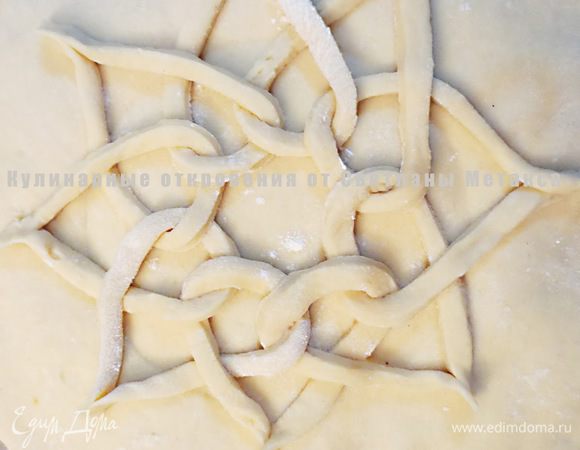 Маленькую часть теста раскатываем в длину и нарезаем из нее 8 полосок, ширина которых примерно 6 мм.
Выкладываем полоски на поверхность верхней лепешки в виде петли, накладывая один конец на другой, по порядку пропуская последующую полоску теста через предыдущую петлю. Соединяем концы каждой петли, формируем снежинку.