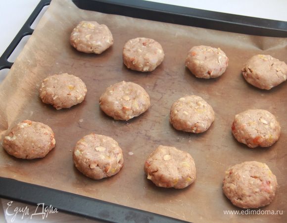 Тесто слепить в шар, а затем скатать в колбаску, которую разделить на 12 частей. Каждую часть скатать в колобок, а затем приплющить. Выложить заготовки пряников на антипригарный лист.