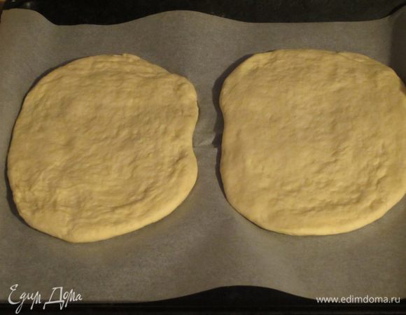 Вымесить тесто еще раз и разделить на две одинаковые части. Сформирoвать две фокаччи овальной формы и выложить на противень с пергаментом.