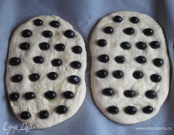 Распределить сверху оливки, хорошо вдавливая в тесто.  Сбрызнуть оливковым маслом, посыпать солью (лучше крупной) и выпекать в разогретой до 220°С духовке 25 минут.