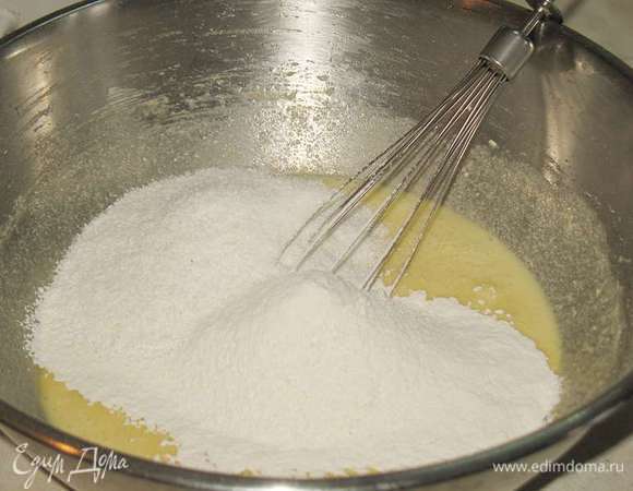 К муке добавить разрыхлитель и просеять. К маслянно-яичной массе добавить кокосовую стружку и просеянную муку с разрыхлителем. Перемешать до однородности. 