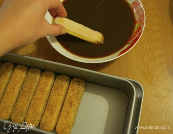 Теперь начинаем собирать наш десерт. Обычно я использую квадратную форму для такого типа десертов, можно взять и круглую (тогда смоченные в пропитке савоярди прийдется подрезать). На этот раз я взяла продолговатую форму для кексов со съемными бортами - очень удобно! Печенье савоярди по одному смачиваем в пропитке-сиропе. Главное делать это достаточно быстро, чтобы они не раскисли!!! Выкладываем их ровным слоем в форму, сахарной стороной вверх.