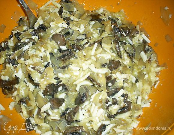 В отдельную емкость натираем плавленый и твердый сыр на крупной терке, добавляем яйца и белок. Желток оставляем для смазывания верха пирога. 
Добавляем сюда же содержимое сковороды. Все тщательно перемешиваем до однородности.