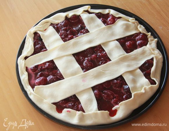 Оставшееся тесто слегка раскатать, нарезать на широкие полоски, выложить на пирог в виде решётки. Полоски и бортики смазать молоком, присыпать сахаром.