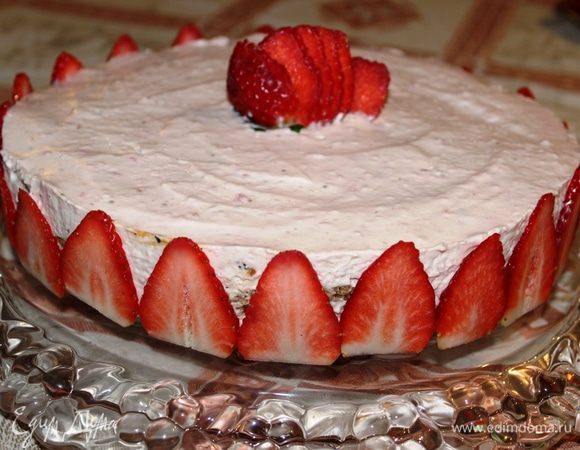 Аккуратно перенести торт на сервировочное блюдо. Для украшения клубнику лучше брать крупную. Нарезать ее пластинками и разместить их по всему периметру. Далее украсить торт по своему желанию и вкусу. 