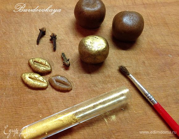 Готовим декор. Лепим из пряничного теста или марципана шарики, слегка сплющиваем их пальцами, лепим листики. Сухую кисть окунаем в кандурин, стряхиваем излишки и покрываем им наши яблочки и листочки. Сверху яблочка втыкаем бутон гвоздики и прикрепляем листик. Готово!