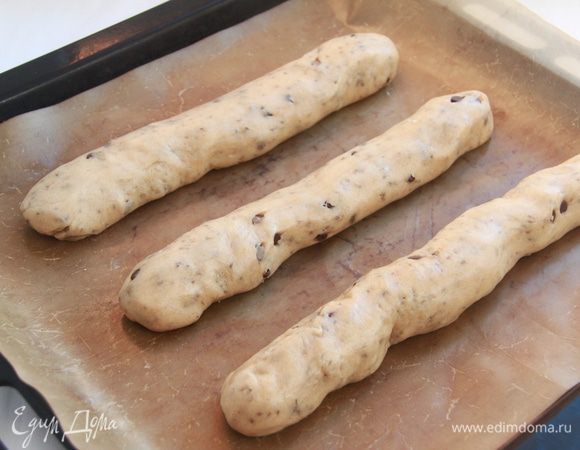 Тесто выложить на рабочую поверхность, присыпанную мукой. Разделить на три равные части. Сформировать три рулона (колбаски) диаметром 4 см и выложить их на антипригарный лист (пекарскую бумагу).