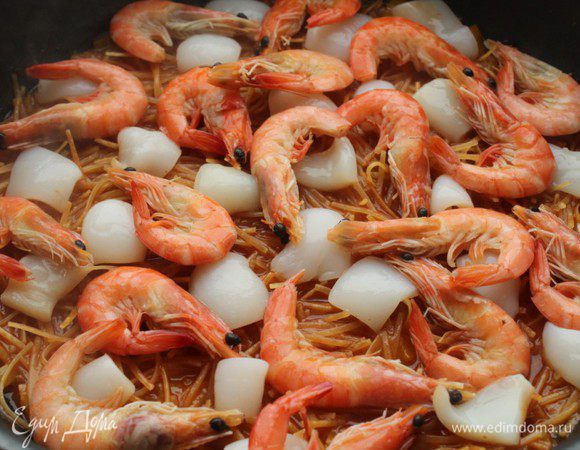 Когда бОльшая часть жидкости впитается, добавить кальмар и креветки. Накрыть крышкой и готовить еще 4-5 минут.