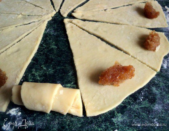 Положить на каждый треугольник 1 чайную ложку начинки и скатать в рулетик. У меня начинка – густое розовое варенье и варенье из айвы. Для начинки также можно использовать измельченные орехи, изюм, вишни.