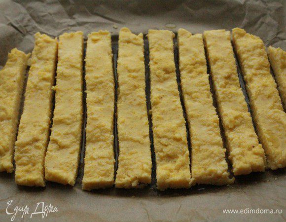 Застывшую поленту перенести на противень. При помощи острого ножа нарезать тонкими брусками. Смазать поверхность маслом и запекать 20 минут при температуре 180 градусов. За 5 минут до окончания выпечки можно включить функцию ГРИЛЬ, если таковая имеется.