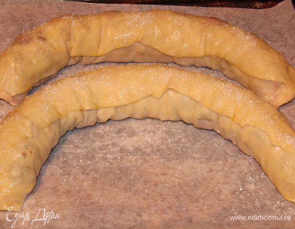 Выкладываем на противень, выстеленный пергаментом, смазываем маслом и посыпаем сахаром (без фанатизма).