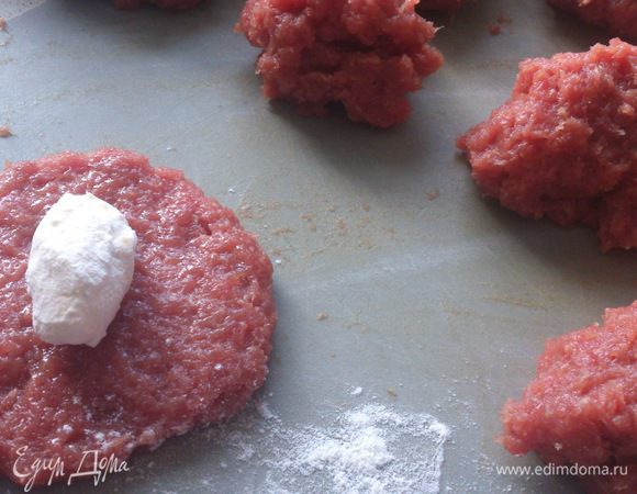 Разделить фарш на 11 частей. На одну котлету получается около 100 г фарша. Размять в лепешку и смазать немного яйцом. Кусочек масла обвалять в муке и положить в середину.