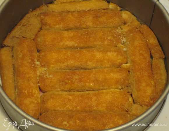 Сборка торта: Кольцо от разъёмной формы торта поставить на блюдо. Быстро обмакнуть в пропитке печенье с двух сторон (полностью не погружать) и выложить в форму один слой.