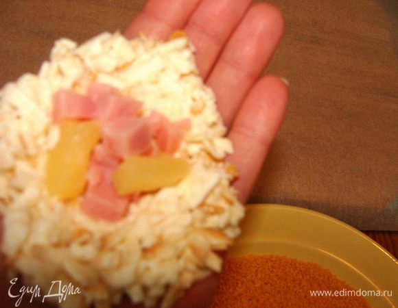 Берем столовую ложку с горкой сырной смеси, делаем лепешку, кладем начинку, формируем шарик.